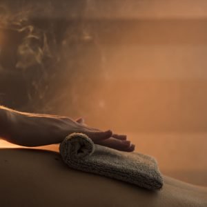 close-up-therapist-hand-massaging-woman-s-back-with-hot-towel-spa